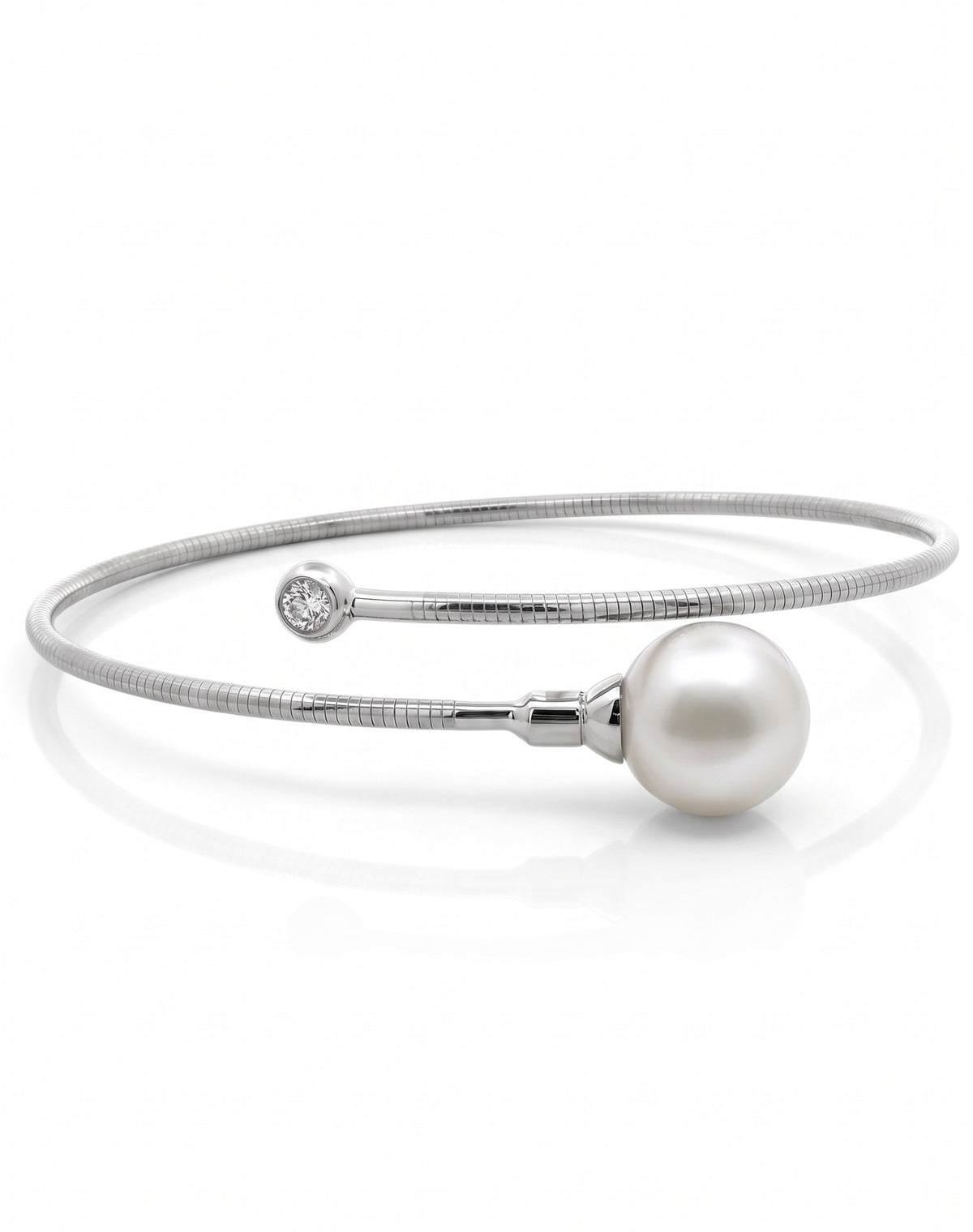 Silver bypass cuff bracelet featuring a large white pearl on one end and a bezel-set round diamond on the other, centered on a plain white background.
